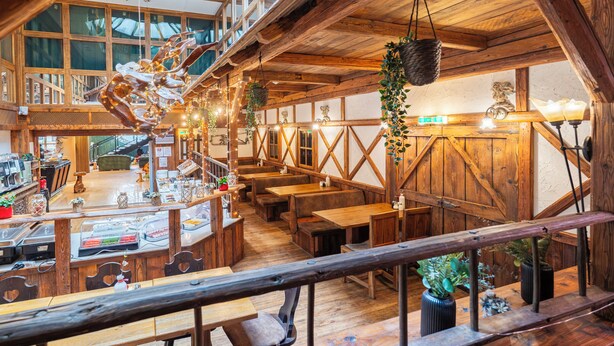 Een restaurant met houten inrichting, hoge plafonds en uitzicht op de stad.