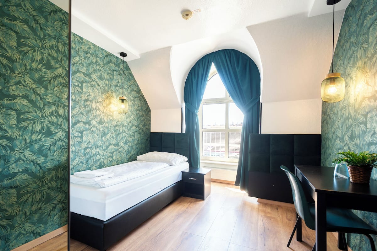 Un dormitorio con cama, escritorio y ventana con cortinas.