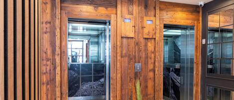 Un vestíbulo moderno con paneles de madera, una planta en maceta y un ascensor.