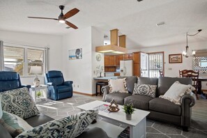 A modern living room with a sofa, chairs, a coffee table, and a ceiling fan.
