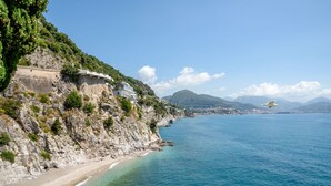 Un paisaje costero con un acantilado rocoso, una playa y vistas al mar.