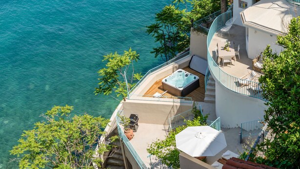 Un edificio alto con un patio en la azotea y vista a un cuerpo de agua.