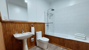 Ein Badezimmer mit einem Holzkosmetikschrank, einem weißen Waschbecken, einer Toilette und einer Badewanne.