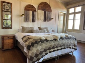 A neatly arranged bedroom with a large bed, a wooden nightstand, and a wall-mounted lamp. - Estancia Río Penitente (Laguna Blanca)