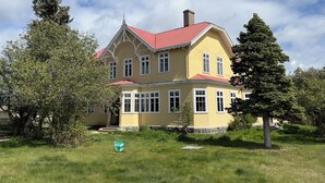 Ein großes, gelbes Gebäude mit rotem Dach, umgeben von Bäumen und einer Grünfläche.