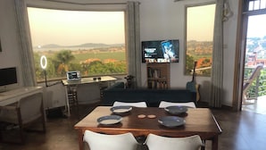 Una sala de estar moderna con comedor, televisor y laptop sobre un escritorio.