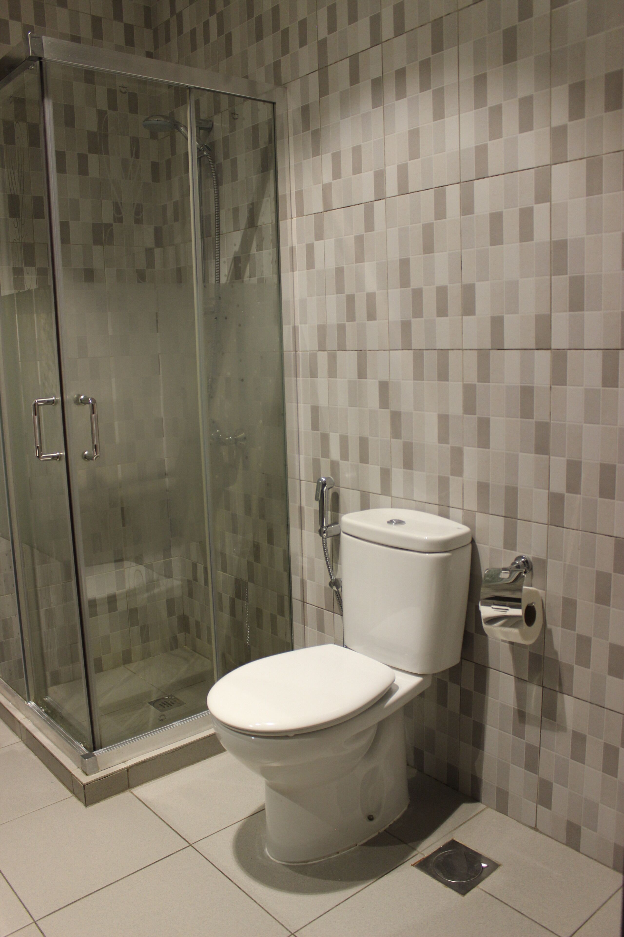 A bathroom with a glass-enclosed shower, a toilet, and tiled walls.