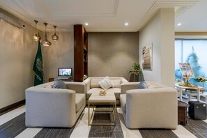A modern living room with a sofa set, a coffee table, pendant lights, a flag, and a television.