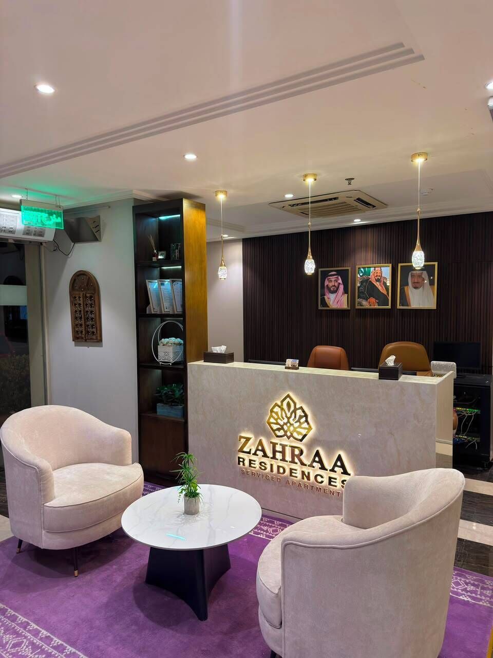 Zona de recepción con mostrador, dos sillones, una mesita y una planta decorativa.