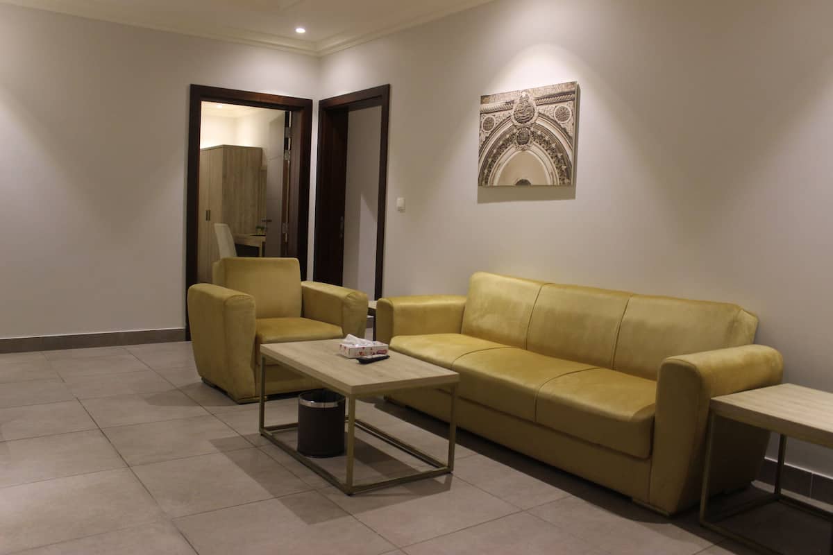 Una sala de estar con un sofá amarillo, una mesita y un cubo de basura.