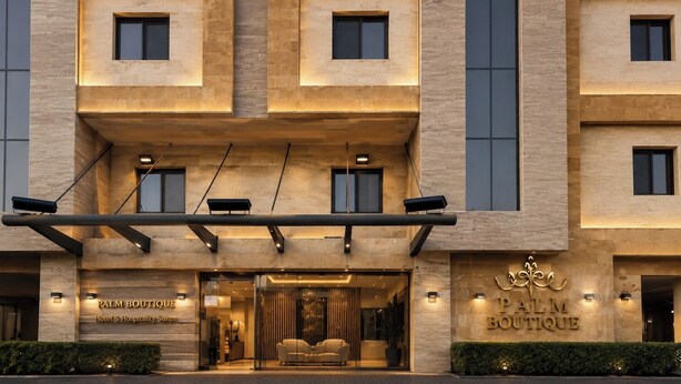 Entrada de un hotel con un letrero que dice 'Palm Boutique Hotel & Hospitality Suites'.
