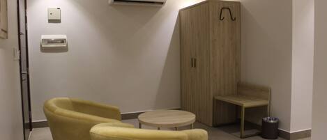 A room with a wooden cabinet, a small round table, and two yellow chairs.