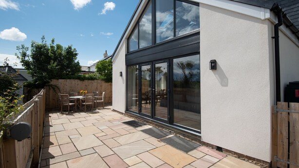 Ein modernes Haus mit einer großen Glasdoor und einer Terrasse mit Steinböden.
