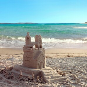Un château de sable sur une plage, avec l’océan en arrière-plan.