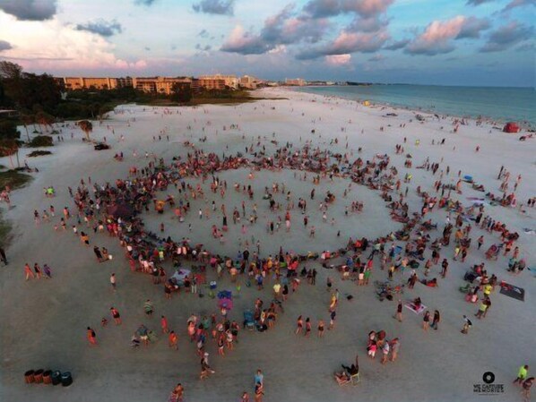 Ein Strand, auf dem Menschen im Sand eine Herzform bilden.