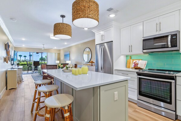 A modern kitchen with white cabinets, stainless steel appliances, and a large island with stools.