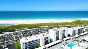 A high-rise hotel with multiple parking levels, a swimming pool, and a beach view.