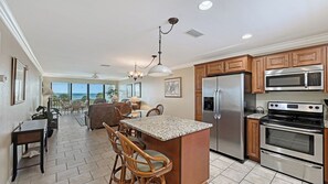 A spacious kitchen with a central island, stainless steel appliances, and a view to the outside.