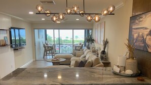 A spacious living area with a large marble island, wooden bar stools, and a balcony with outdoor seating. - Coveted Siesta Key Escape 1 Bed 1 Bath with Gulf Views Steps to Beach (Siesta Key)