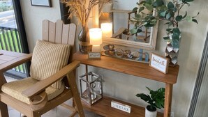A wooden chair with a woven cushion, a small table with a lamp, a mirror, and decorative items including a sign that says "Beach Happy Place". - Coveted Siesta Key Escape 1 Bed 1 Bath with Gulf Views Steps to Beach (Siesta Key)