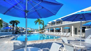 A poolside area with lounge chairs, umbrellas, and a clear blue sky. - Siesta Key Beach 1 Bed 1 Bath Condo Steps to Beach with Full Gulf Views (Sarasota)