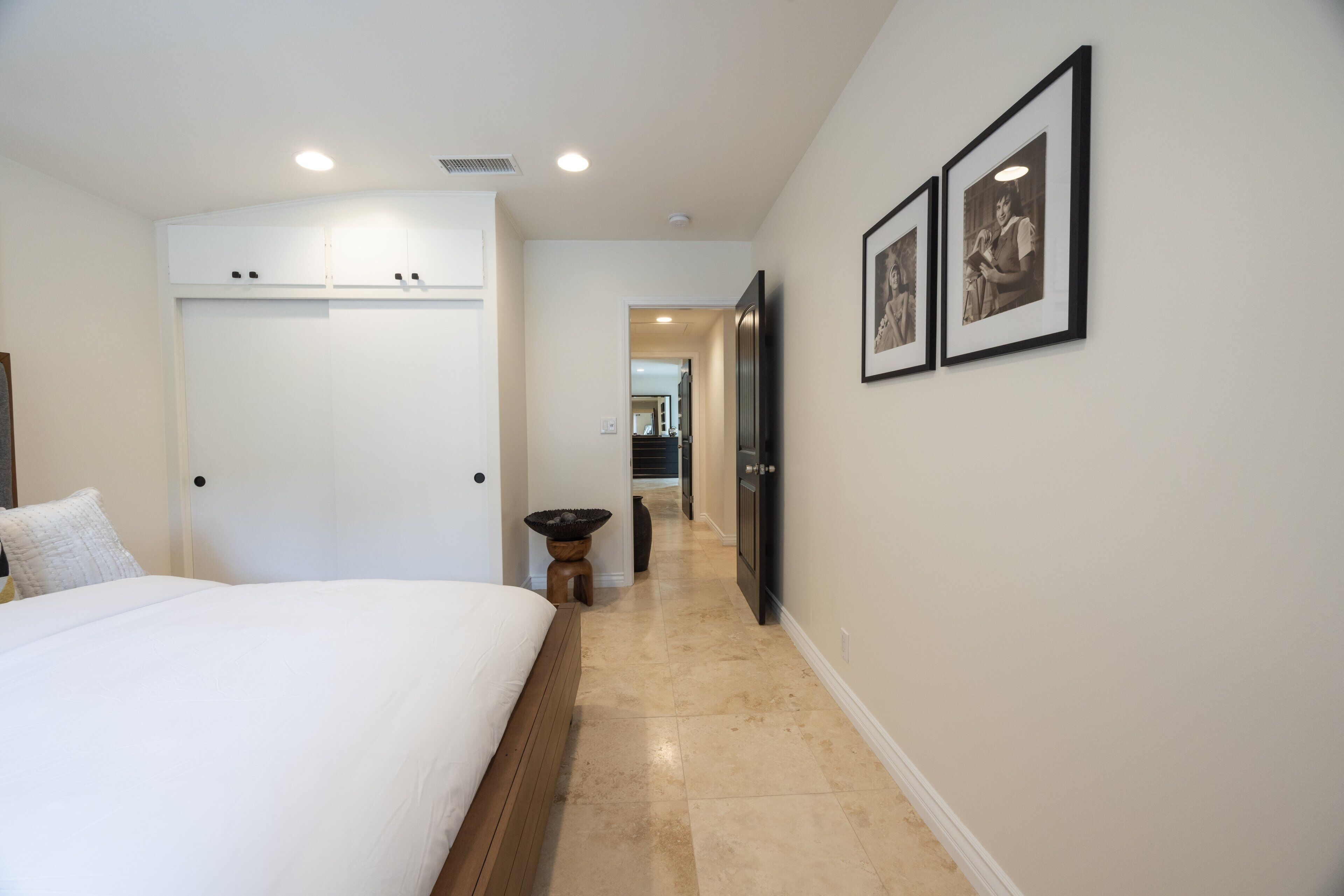 A bedroom with a large bed, a wardrobe, and a hallway leading to a bathroom.