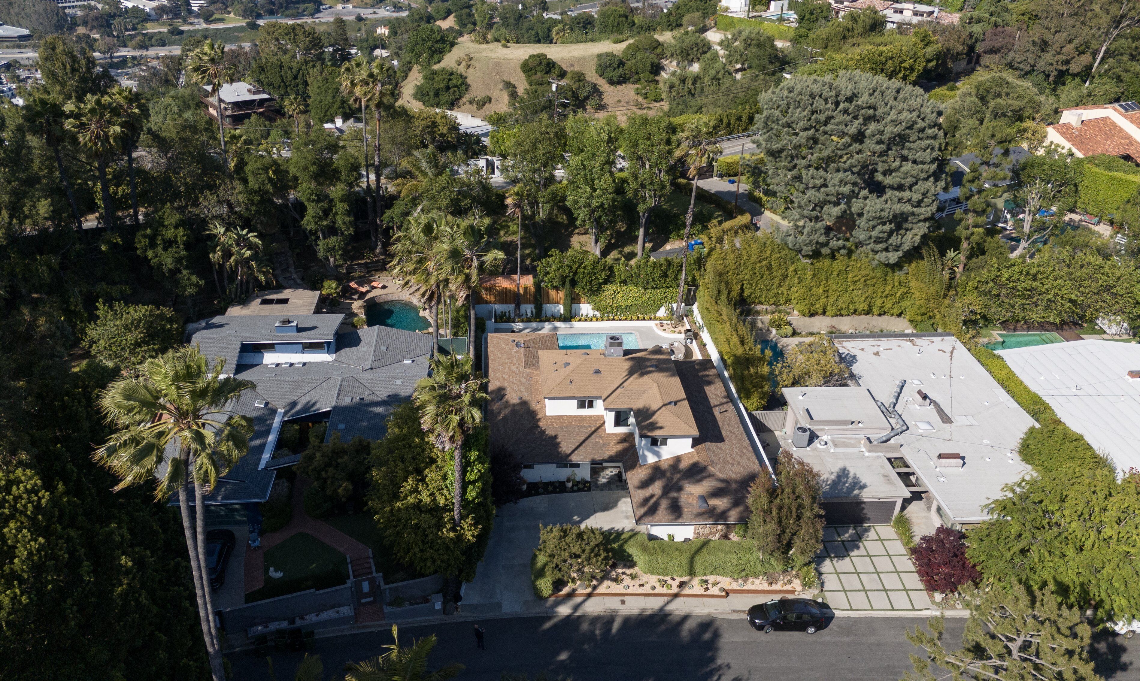 An aerial view of a residential area with houses, a swimming pool, and a parking lot.