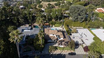 An aerial view of a residential area with houses, a swimming pool, and a parking lot.