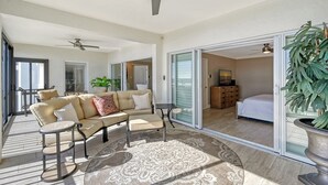 A spacious living area with a beige sofa, a small round table, and a large potted plant.