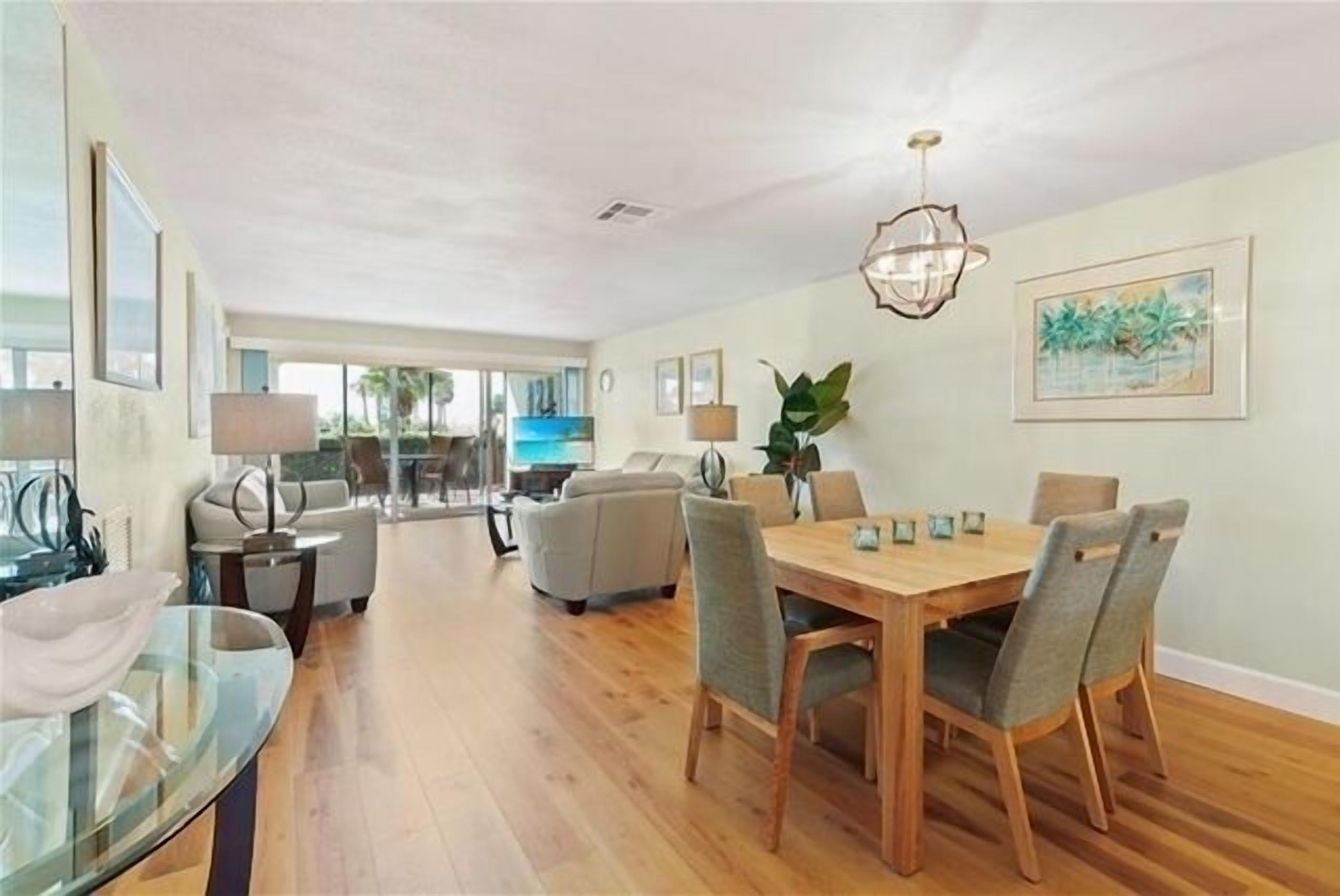 A spacious dining area with a wooden table and chairs, a glass coffee table, and a pendant light.