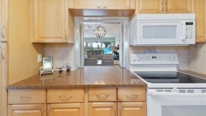 A kitchen with wooden cabinets, a microwave, and a stove. - Siesta Key Beach 2/2 Ground Floor Steps to Beach (Sarasota)