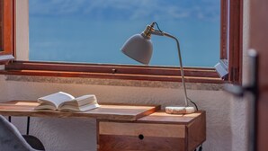 Uma mesa de madeira com um livro aberto, uma lâmpada e uma chávena.