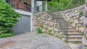 Escadaria de pedra que dá acesso a um deck de madeira com guarda-corpo de metal.