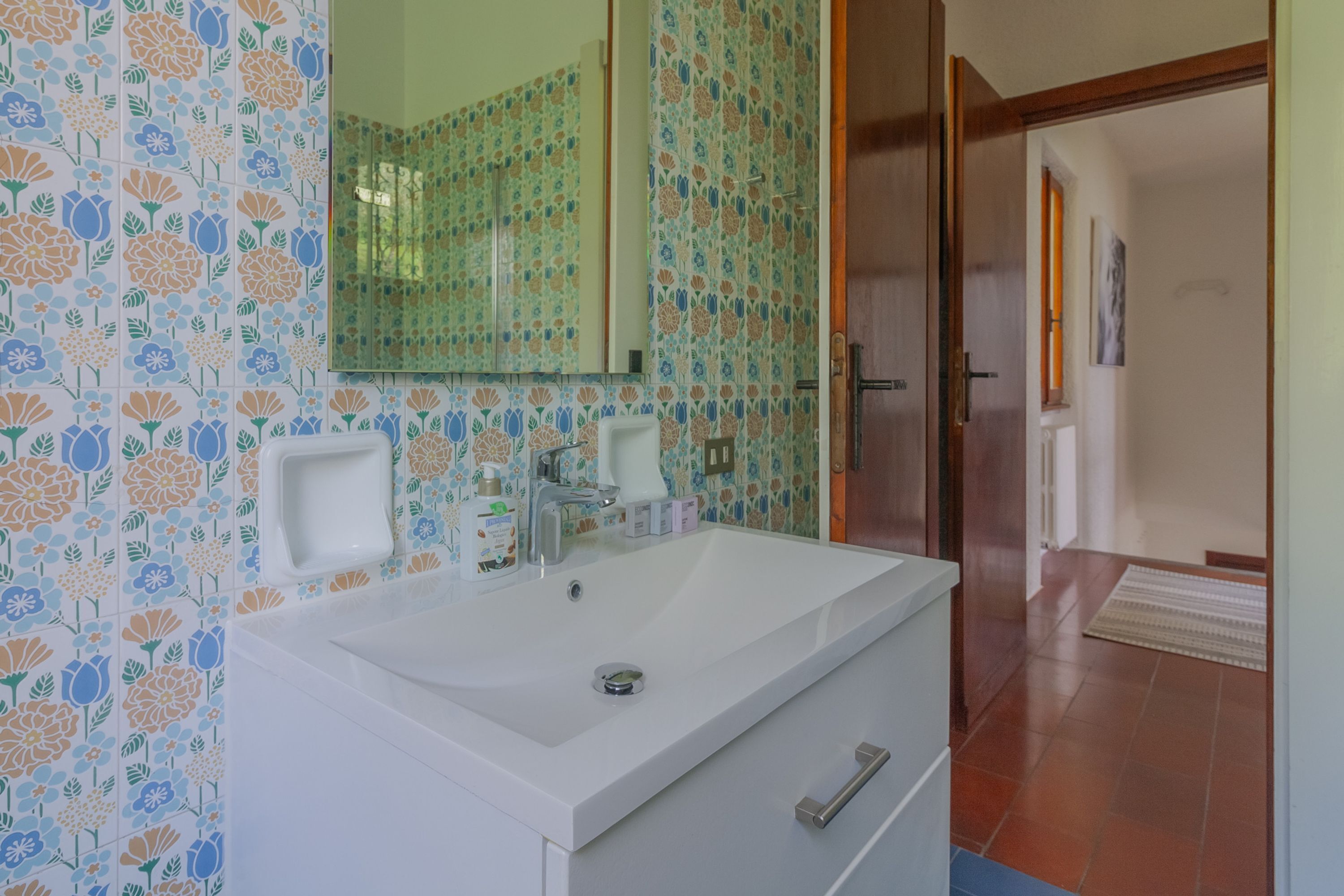 Une salle de bain avec un lavabo blanc, un miroir et un espace douche.