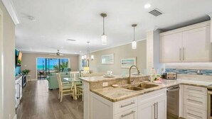 A modern kitchen with a central island, white cabinetry, and pendant lighting.