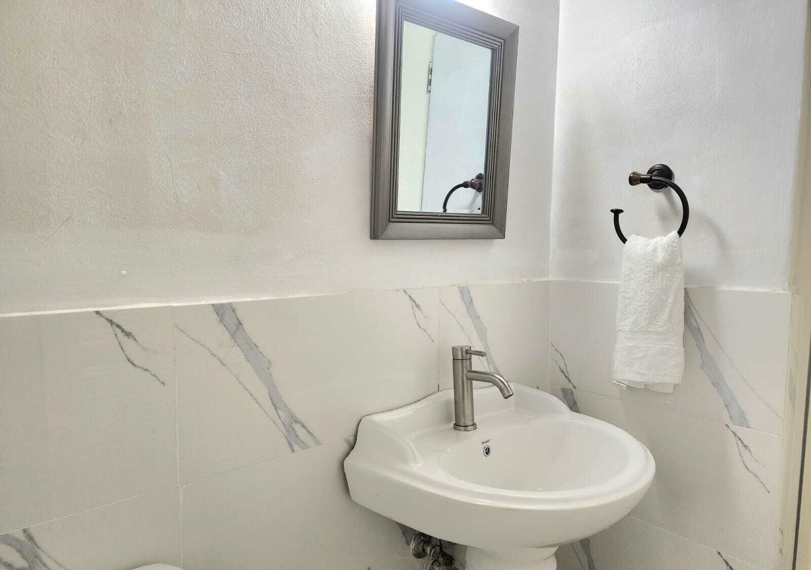 A bathroom with a white sink, a mirror, and a towel rack.