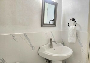 Une salle de bain avec un lavabo blanc, un miroir et un porte-serviettes.