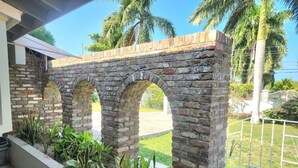 A brick structure with three arches, a concrete planter with various plants, and a metal fence. - Jamaica Dream Villa - Iron Shore Escape (Montego Bay)