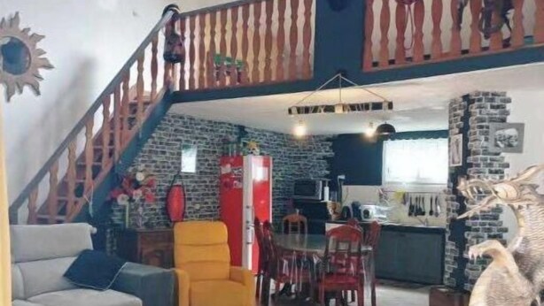 Amplia sala de estar con una escalera que conduce a un nivel superior, un comedor y una cocina visible a través de un acceso abierto.