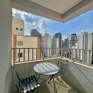Ein Balkon mit Tisch und Stühlen, der einen Blick auf eine Stadt mit verschiedenen Gebäuden bietet.