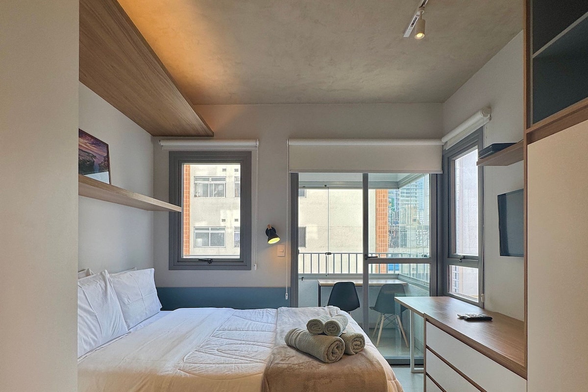 A bedroom with a bed, a desk, a chair, and a window.