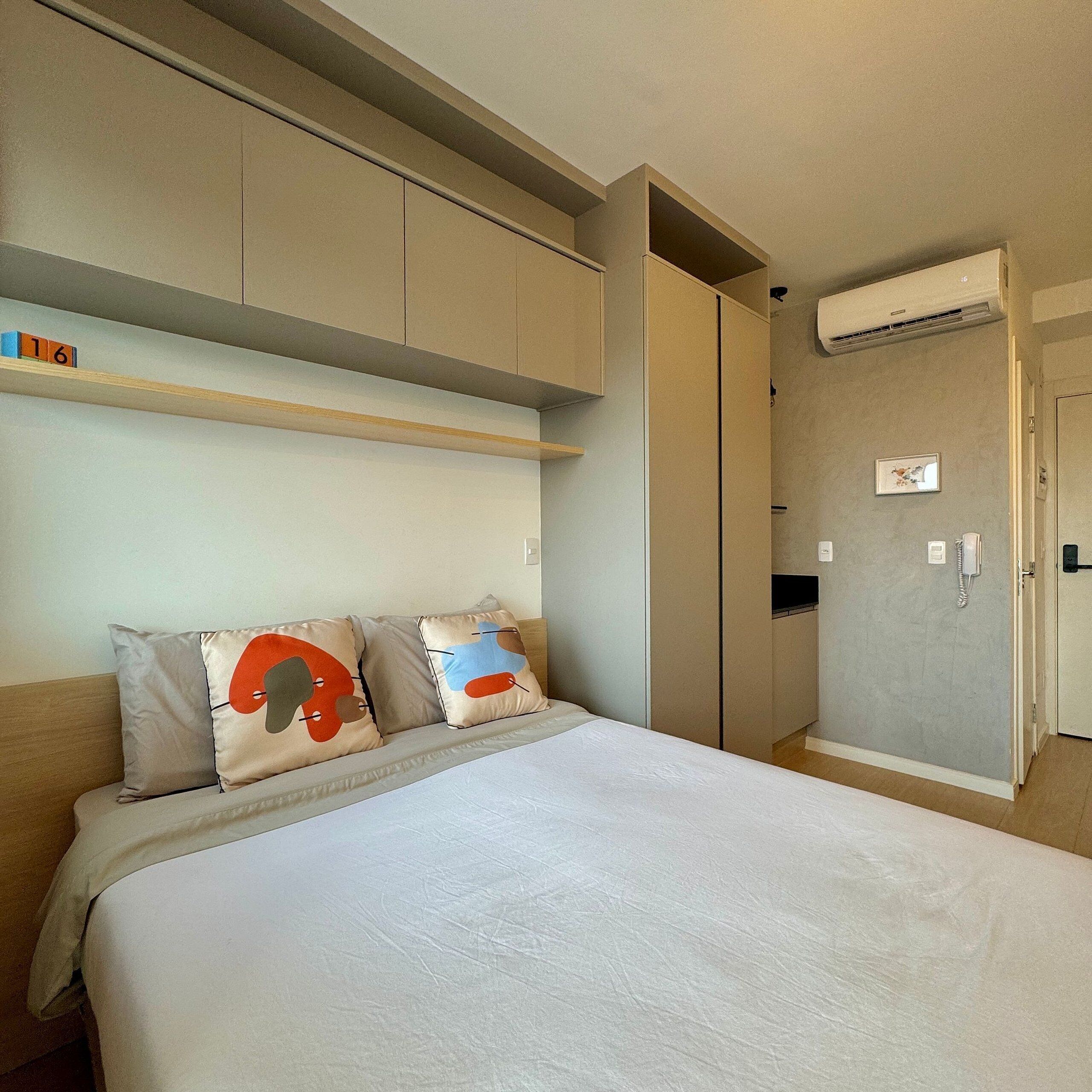 Ein Schlafzimmer mit Bett, Kissen, einem Kleiderschrank und einer Klimaanlage.
