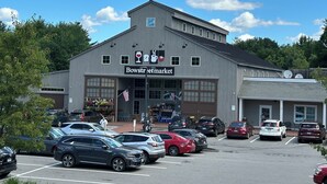 Un edificio con un cartello che riporta la scritta "Bowstreetmarket" e un parcheggio con diverse automobili.