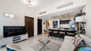 A modern living room with a TV, sofa, and a glass coffee table. - Handsome 1BR in Bay Central Tower (Dubai)
