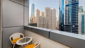 A balcony with two wicker chairs and a glass table, overlooking a cityscape with high-rise buildings. - Handsome 1BR in Bay Central Tower (Dubai)