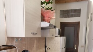 A compact kitchen with a gas stove, a coffee maker, and a microwave. - La Piccola Casetta nel Centro Storico (Iglesias)