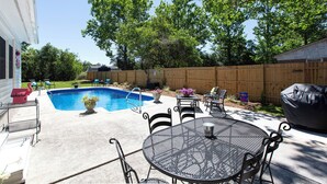 Un patio trasero con piscina, mobiliario de exterior y una valla de madera.