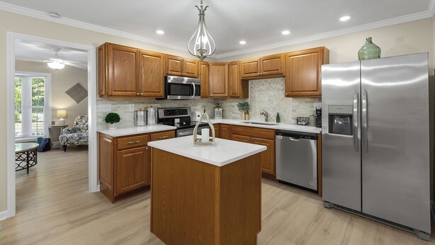 Una cocina moderna con armarios de madera, electrodomésticos de acero inoxidable y una isla central.