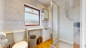 A modern bathroom with a glass shower enclosure, a toilet, a sink, and a window. - Dagenham - 4 Beds - Sleeps 8 - Wifi (Dagenham)