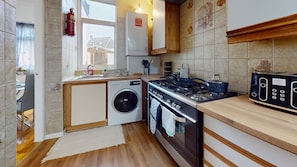 Una cocina compacta con lavadora, estufa y microondas.
